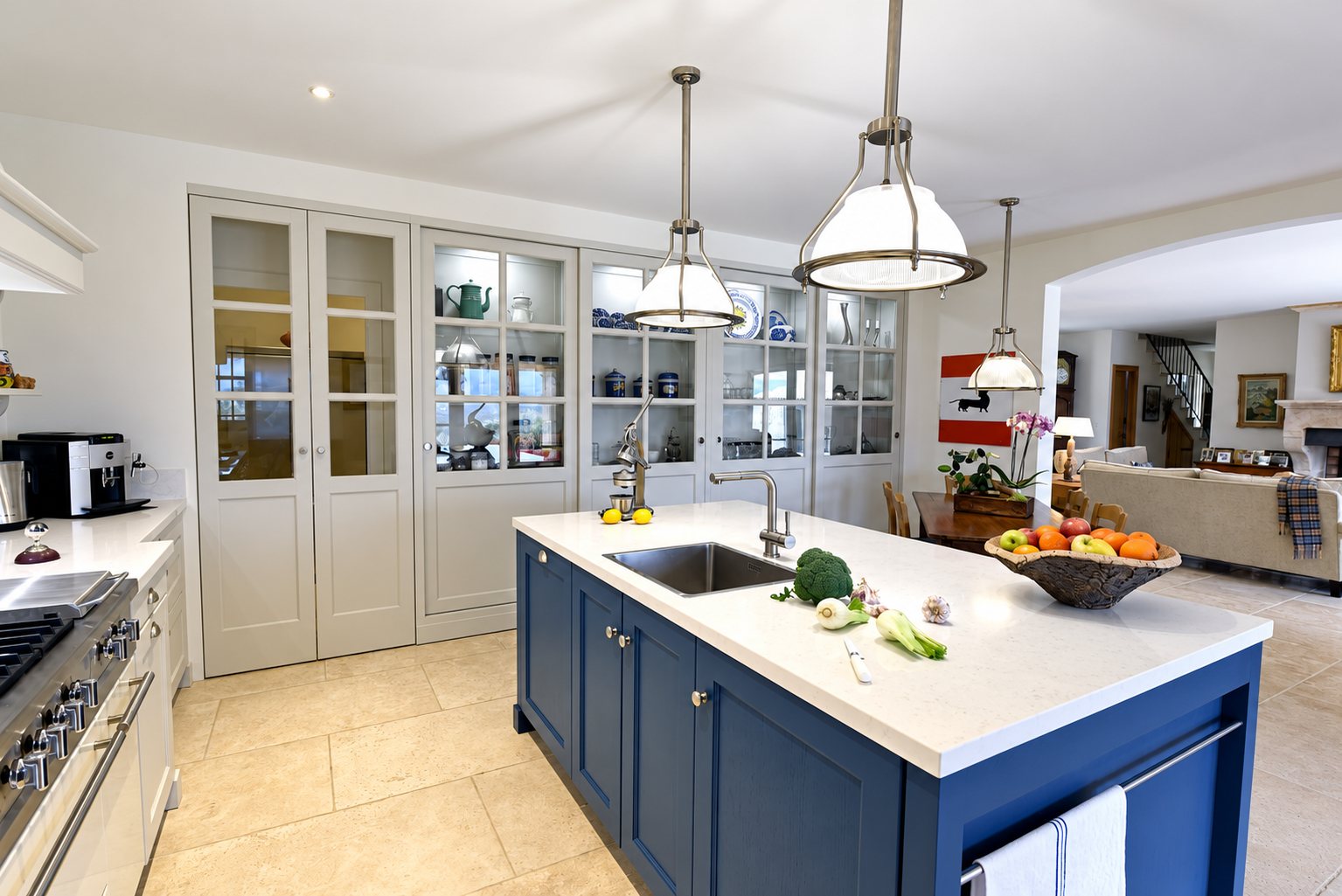 Cuisine à l’îlot central bleu et aux placards vitrés, exemple de rangements réalisés par l’atelier.