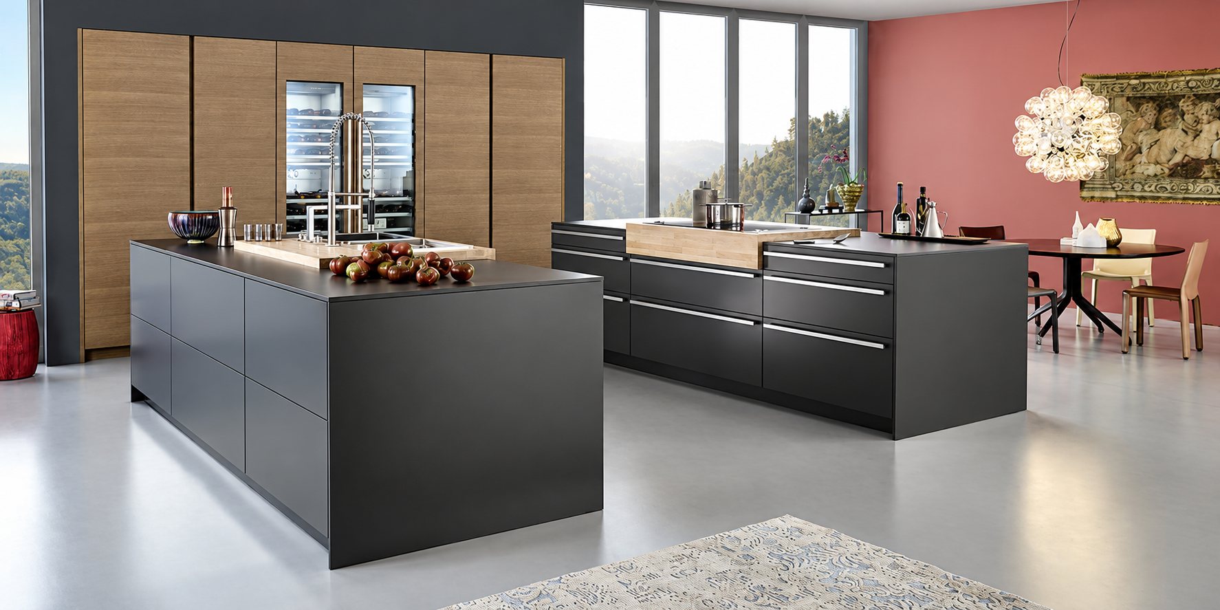 Une cuisine design aux deux grands îlots noir mat, aux hautes armoires en bois et à la salle à manger au mur rose.